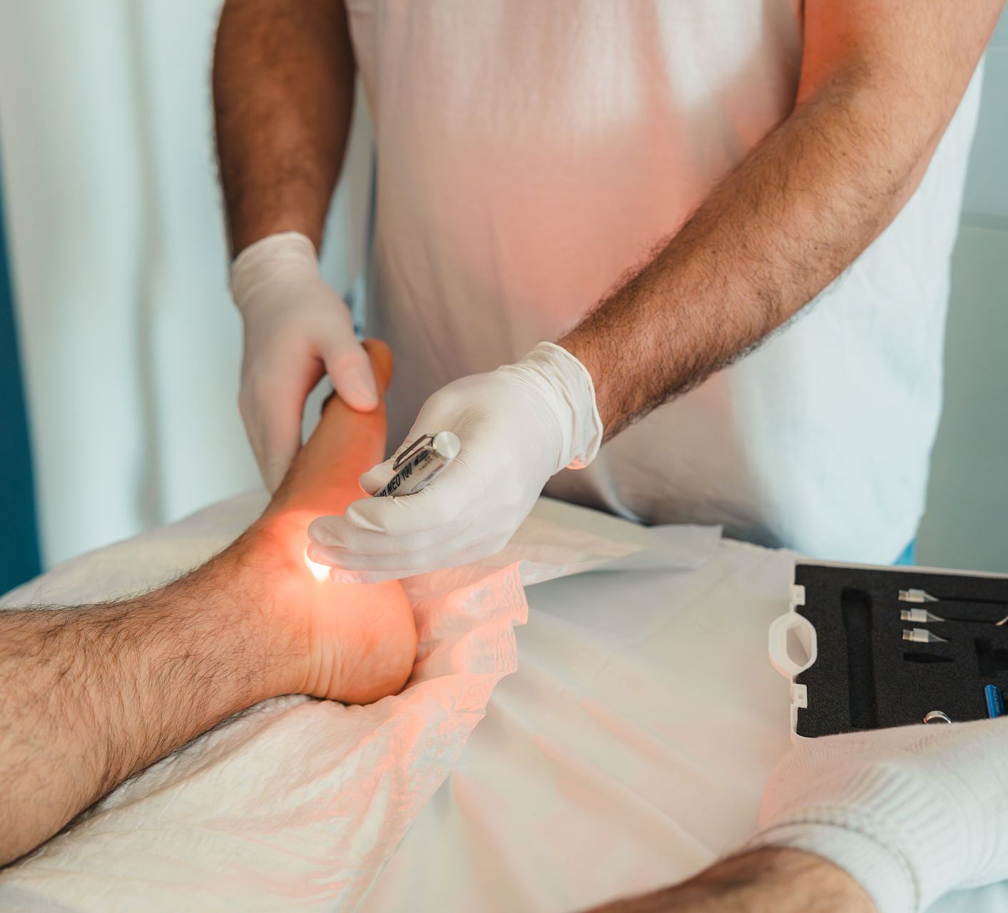 Low-Level Lasertherapie (LLLT) durch DGKP Christian Erber am Fuß eines Patienten