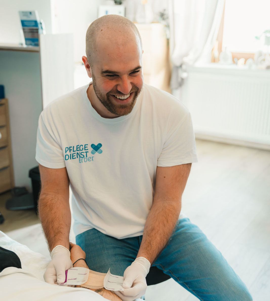 Wundversorgung durch DGKP Christian Erber. Auf dem T-Shirt ist das Logo von Pflegedienst Erber